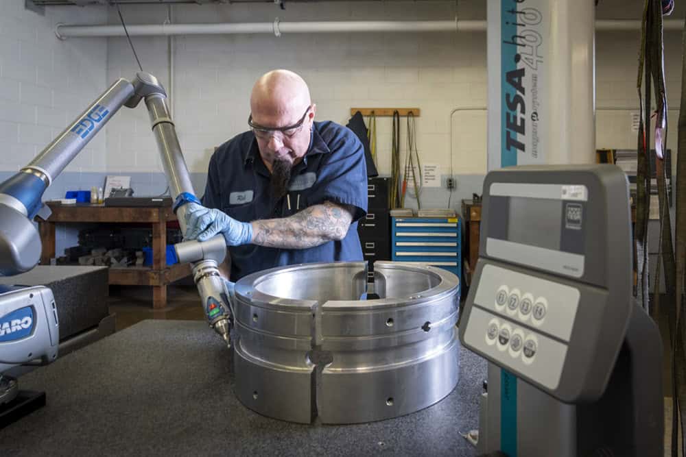 Team member Rick uses 3D measuring tool Faro arm to check dimensions on a larger bearing (about 24" OD) in Quality lab.