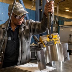 Team member Regina uses hoist to place a bearing half on her workspace to begin deburring.