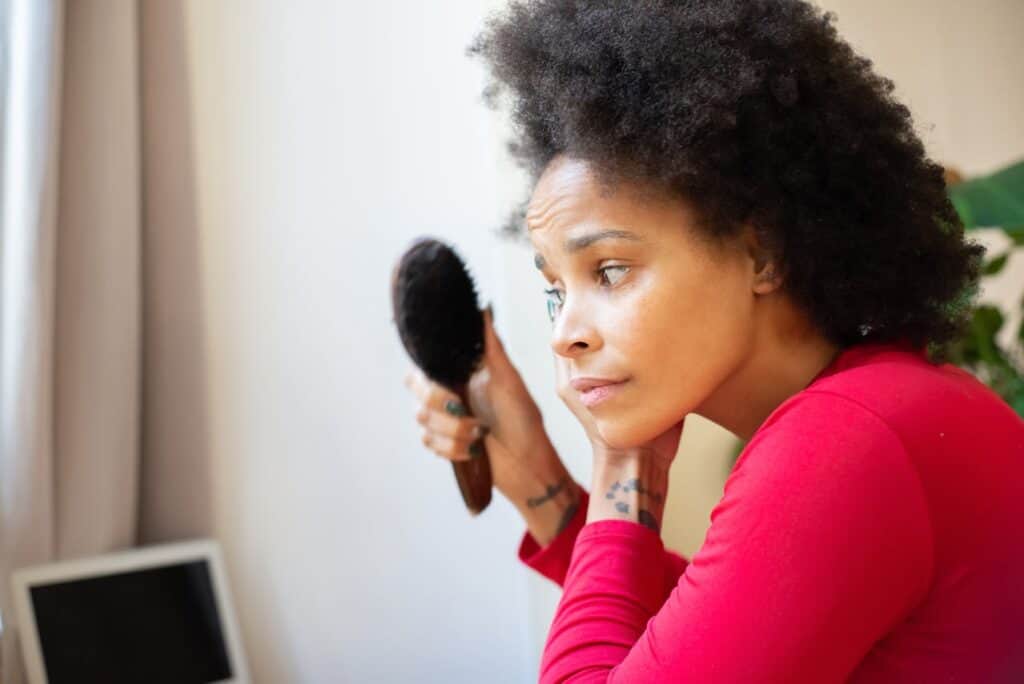 woman checking for hair loss after brushing hair