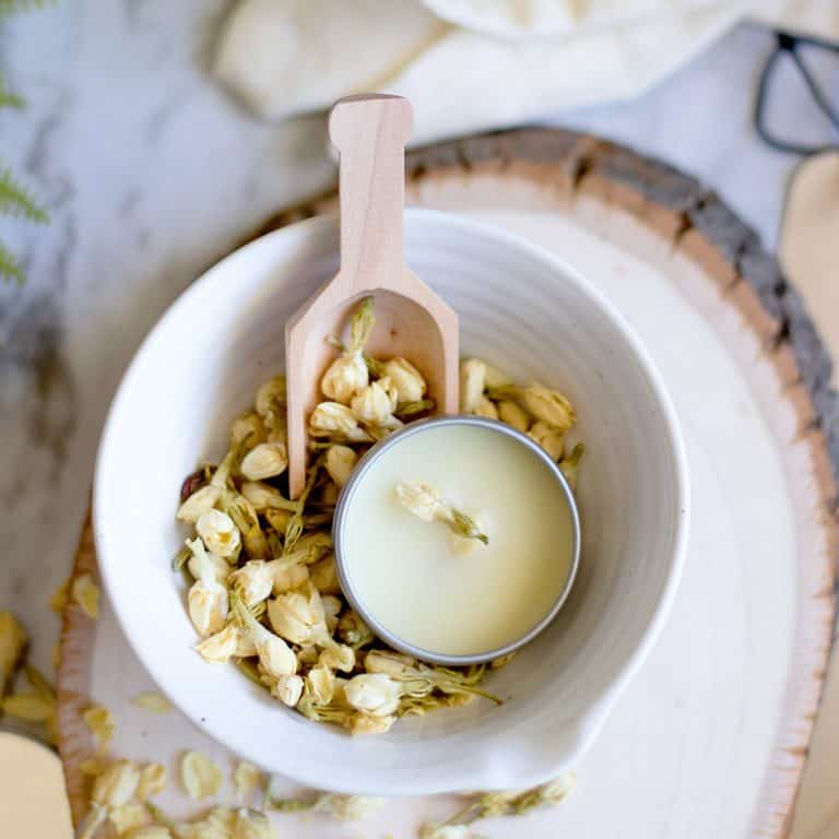 Solid perfume in a round sliver tin with embedded dried jasmine flower bud.
