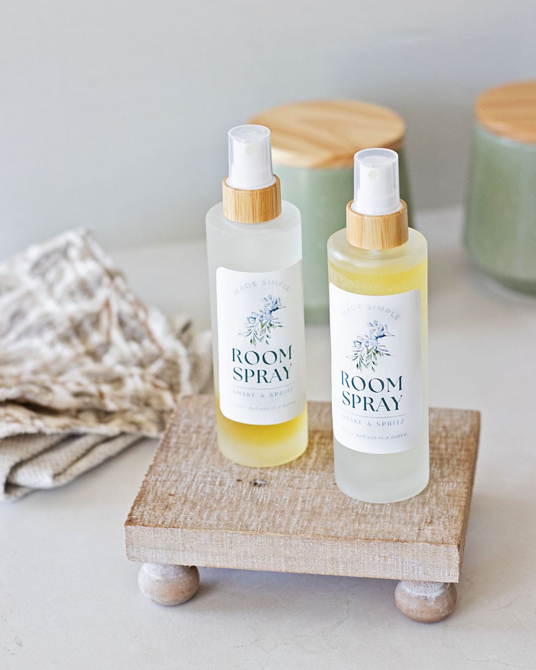 two bottles of room spray with DIY labels on a wood tray