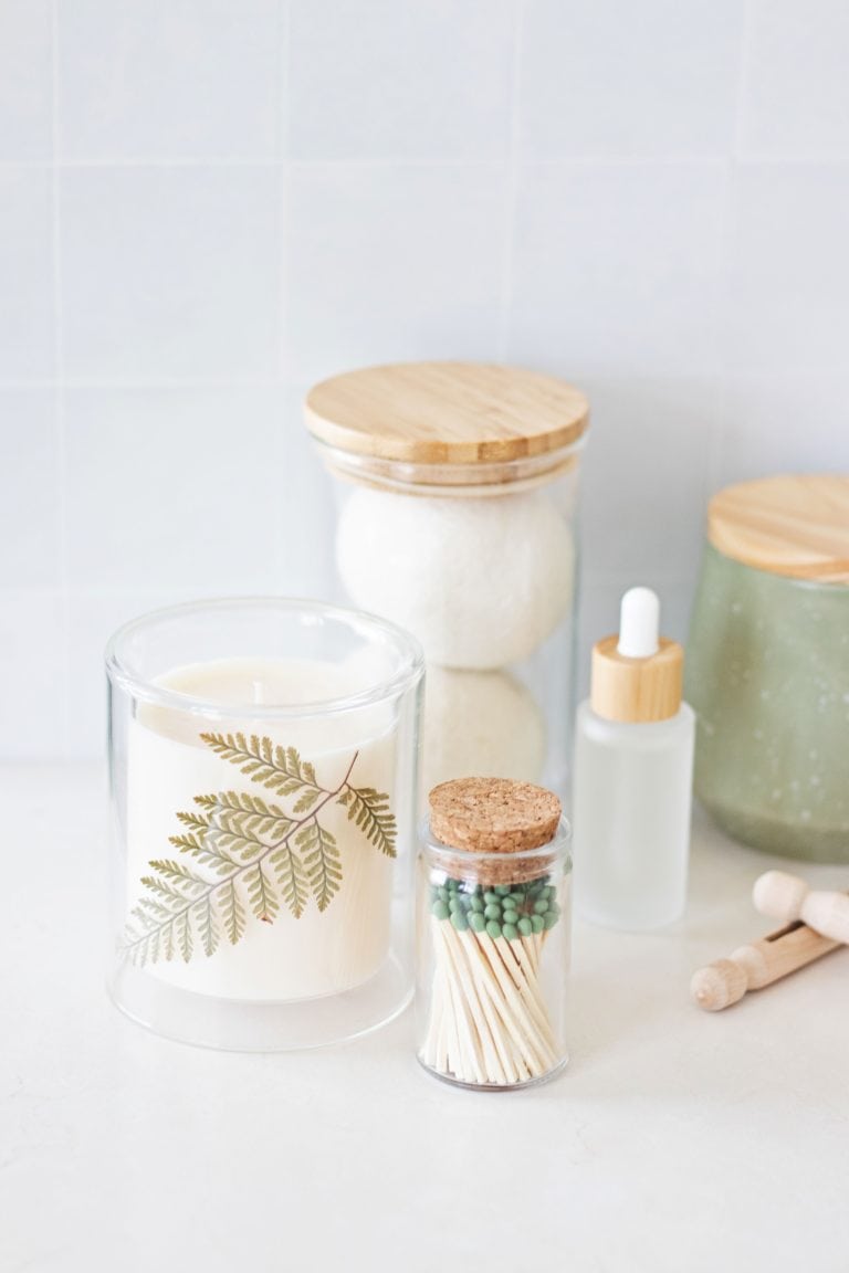laundry counter with a soy wax candle, match jar, room spray bottle, clothespins, wool dryer balls, and jars