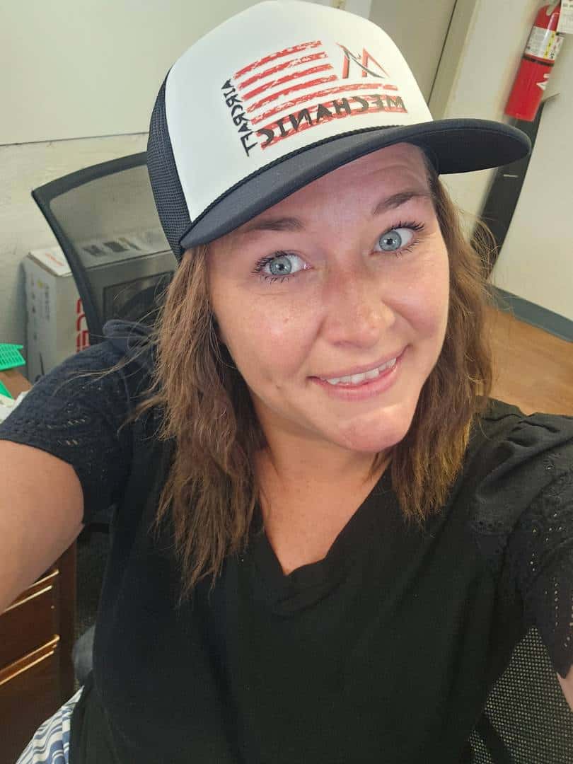 Aviation training professional wearing a cap, smiling in an office environment.
