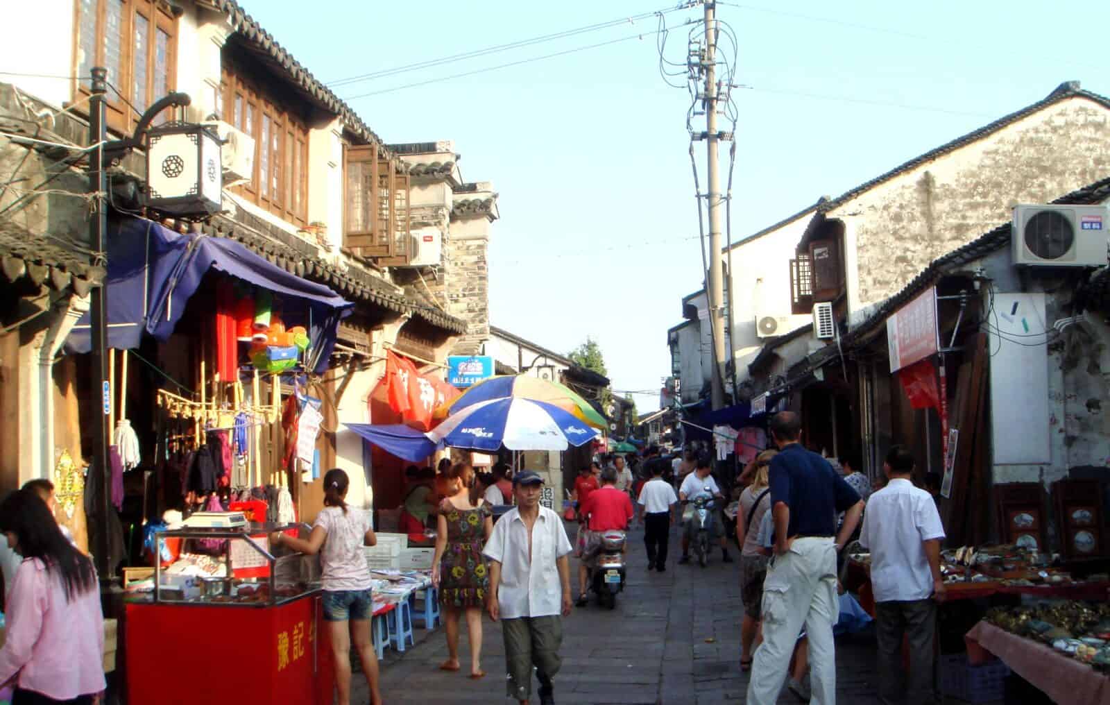 Traditional houses along a narrow canal in Luzhi water town with a small wooden boat on the water
