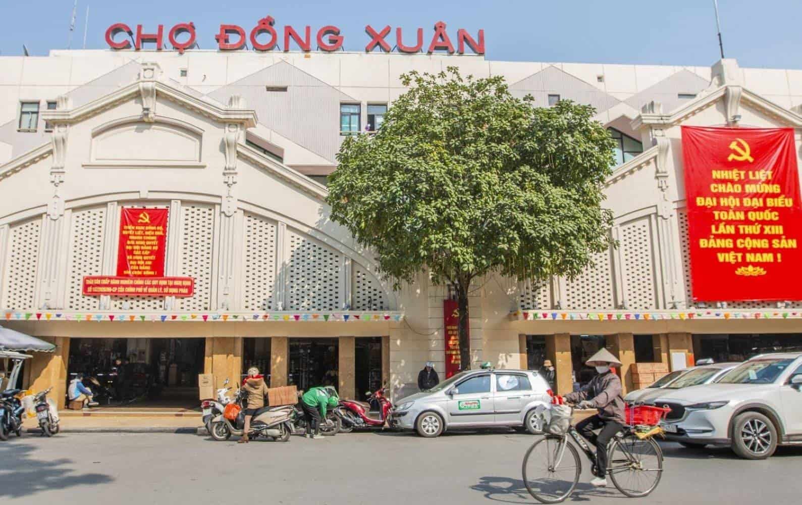 Cyclo driver pedalling a tourist through the busy streets of Hanoi Old Quarter past old colonial buildings and street vendors