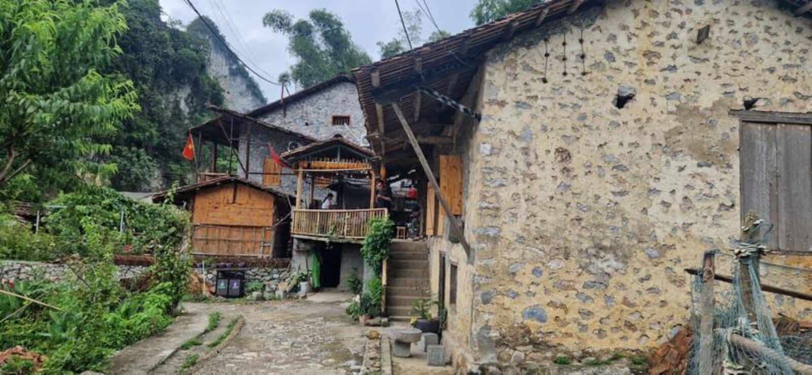 Traditional stilt houses in a rural village near Cao Bang surrounded by karst hills, green fields and scattered trees