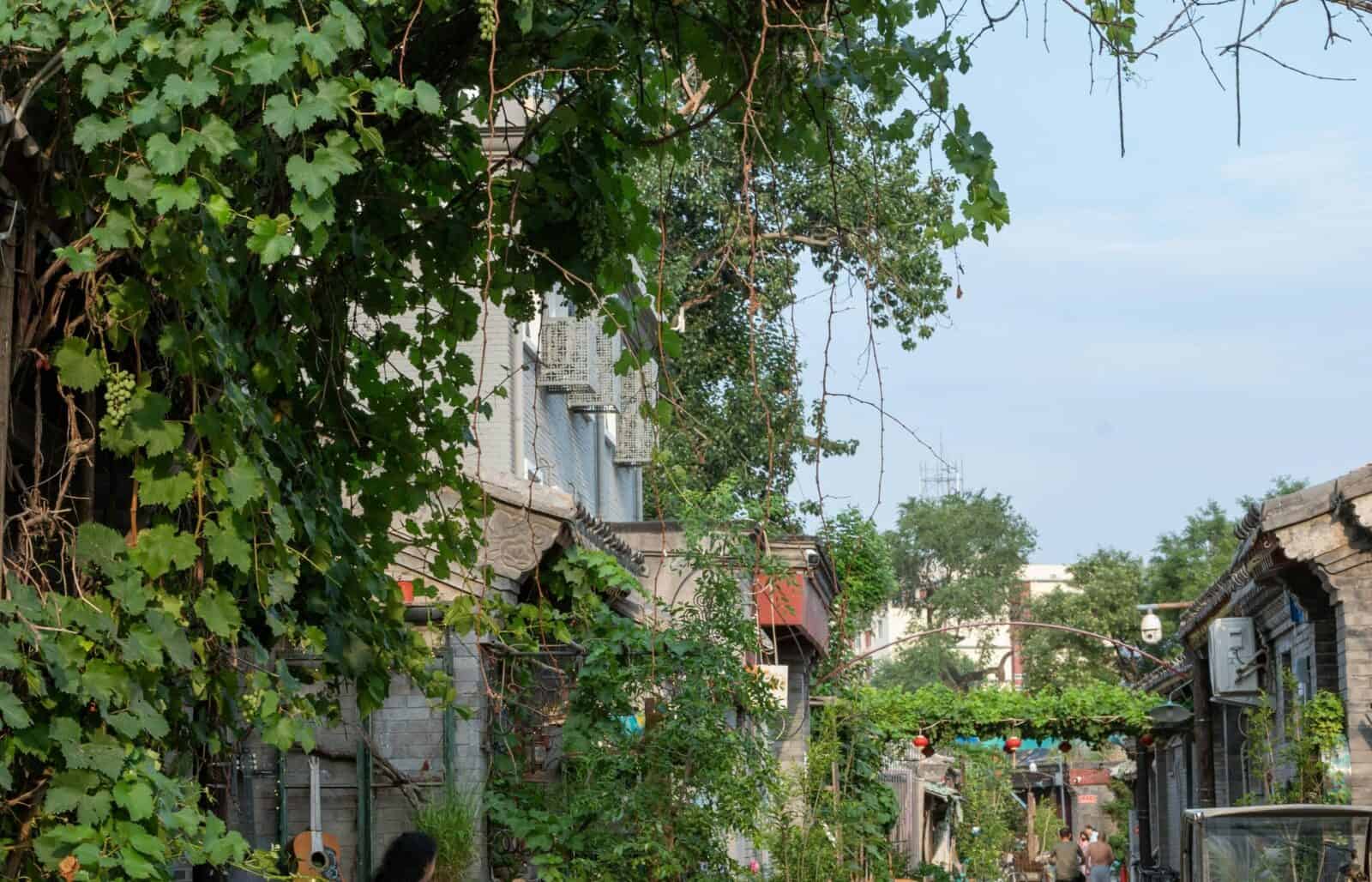 Parents and young child strolling through a traditional hutong alley in Beijing with old brick houses