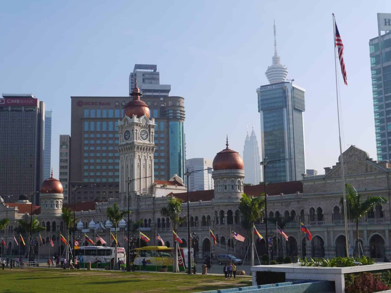 Busy street in central Kuala Lumpur with pedestrians, market stalls and modern high-rises in the background