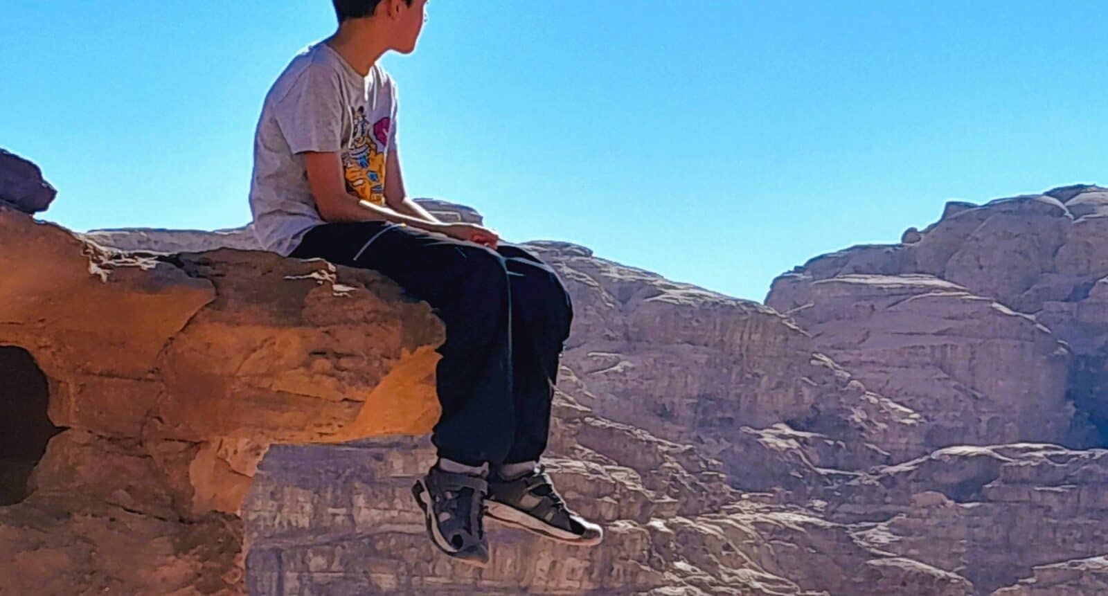 Jeep driving across the red sand and rock formations of Wadi Rum desert under a clear evening sky