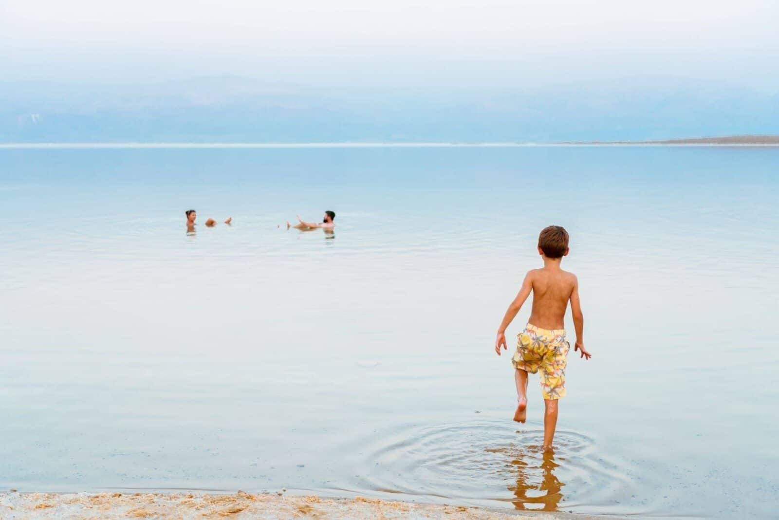Person floating effortlessly on the calm waters of the Dead Sea with mountains in the distance