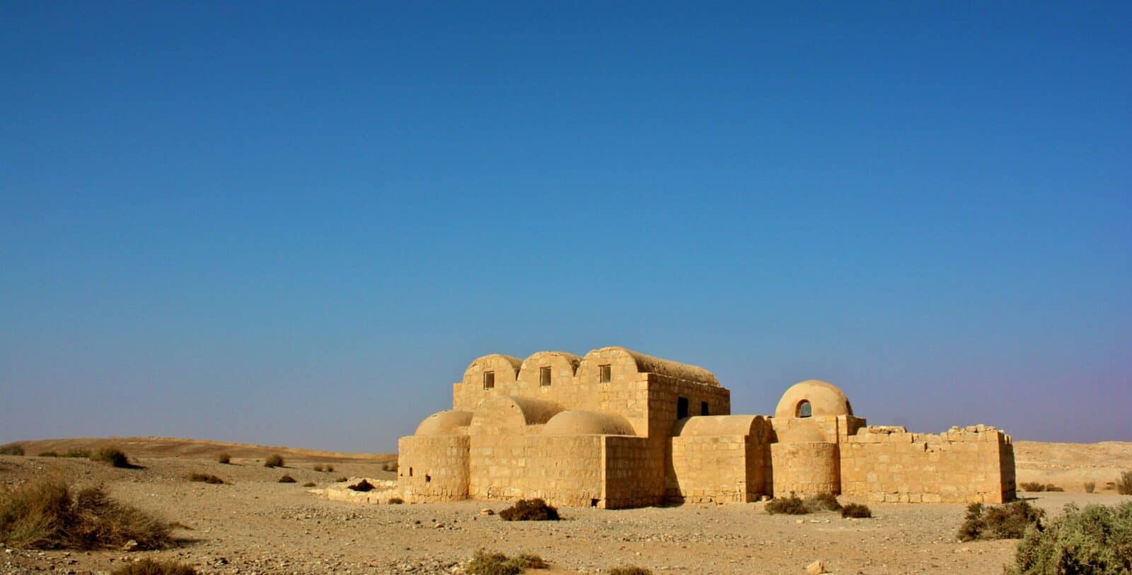 Ancient desert castle in Jordan surrounded by arid landscape and blue sky