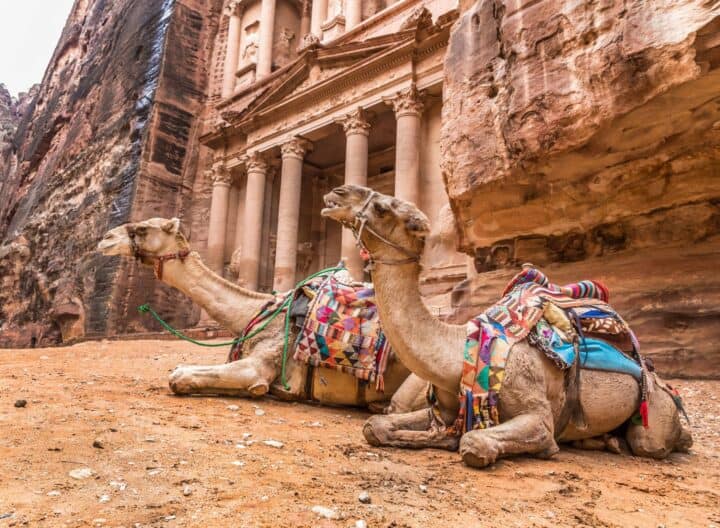 Group of travelers walking through the sandstone canyon Siq towards the Treasury in Petra, Jordan, under a clear blue sky