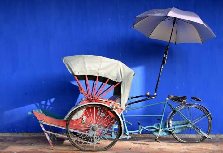 Family standing on a tropical Malaysian beach at sunset, with lush green hills and calm sea in the background
