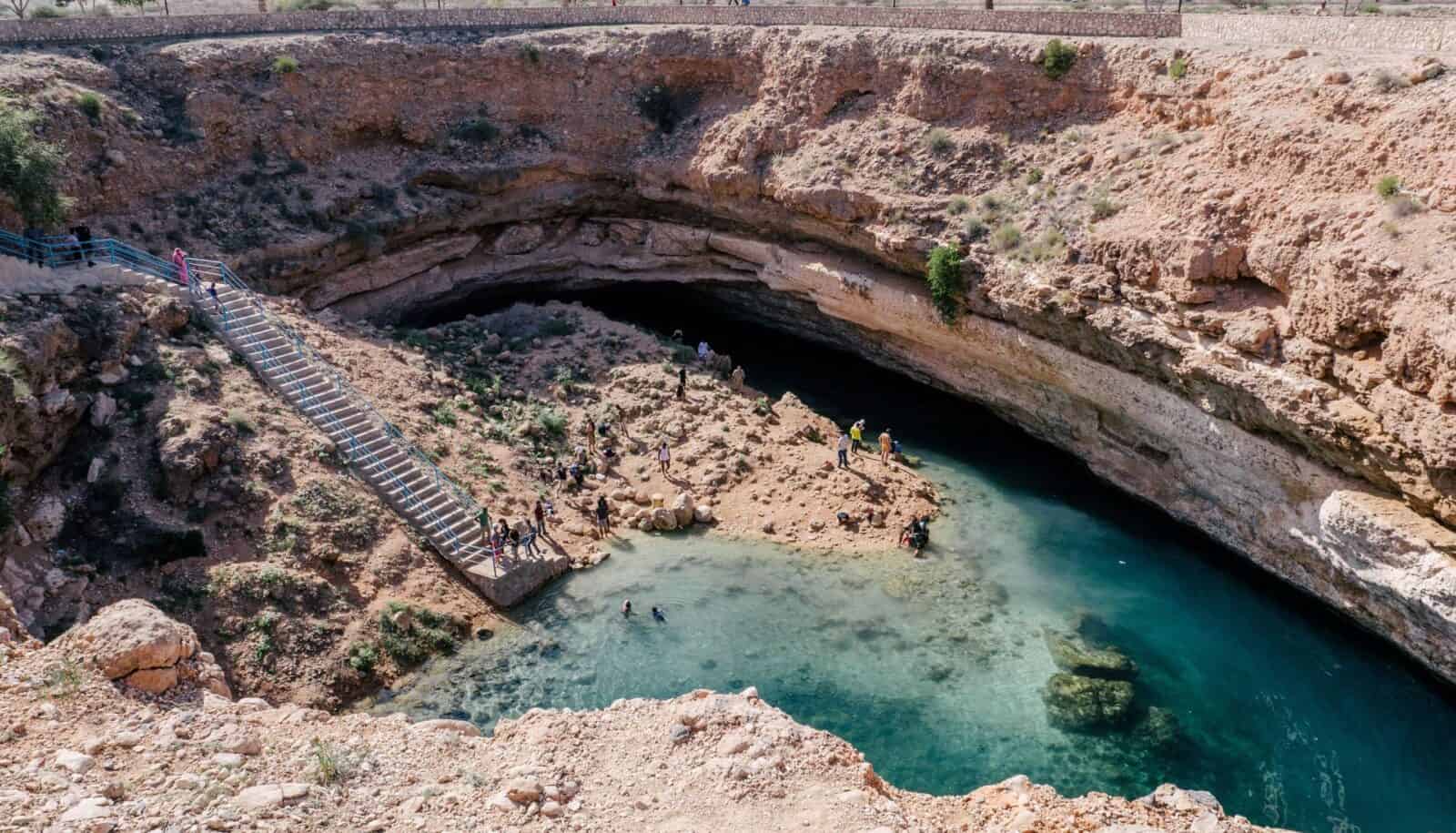 Workers building a traditional wooden dhow boat in an open-air shipyard in Sur, Oman