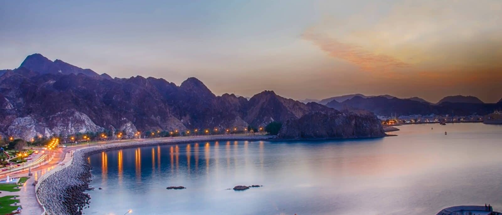 Family relaxing on a sandy beach near Muscat, Oman, with calm blue sea
