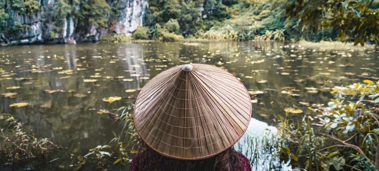 Cyclists riding past rice fields towards karst hills near Nho Quan, Vietnam