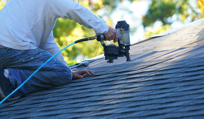 Professional roofer from Perfect Steel Solutions using a nail gun on an asphalt shingle roof in Fort Wayne