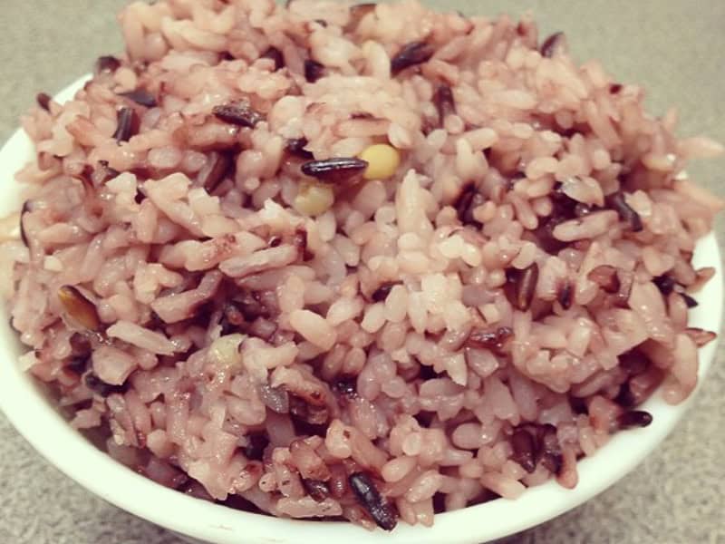 Close up of a white paper bowl of steamed purple rice