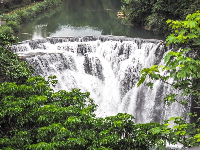 Looking straight on at a waterfall, with some trees blocking the view at the bottom