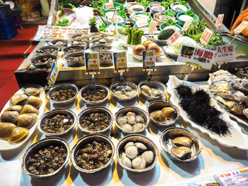 A table with various seafoods on display like sea urchins, clams, and more