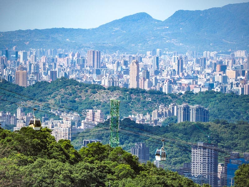 A wide city view, with mountain in the background, and a cable car line at the bottom