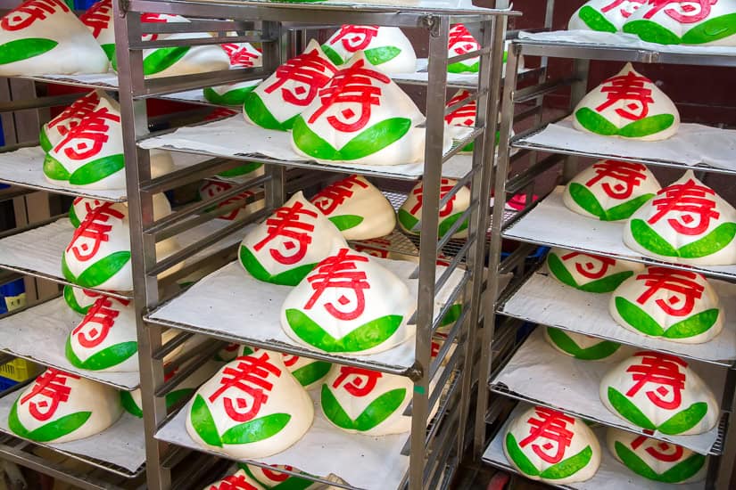 A row of baker's shelves loaded with dome-shaped white cakes with red and green Chinese new year designs on them