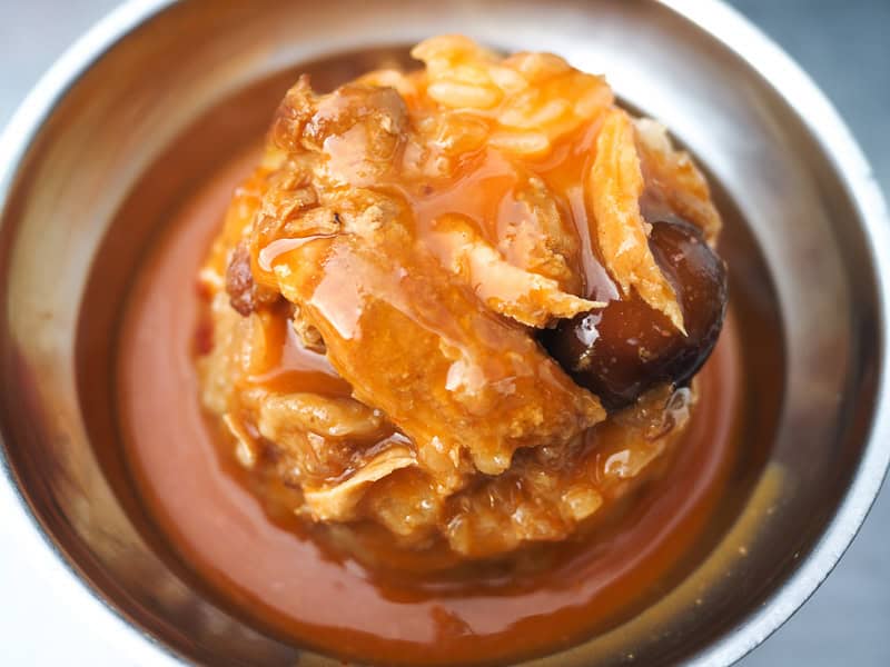 Looking straight down on a Taiwanese dish consisting of a mound of rice topped with chicken and red sauce