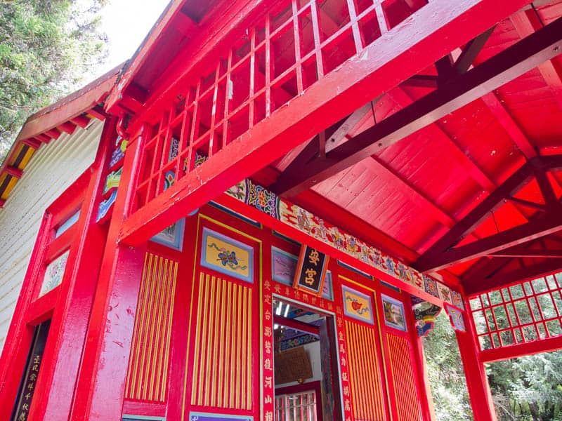 Looking up at a wooden arched temple roof painted bright red