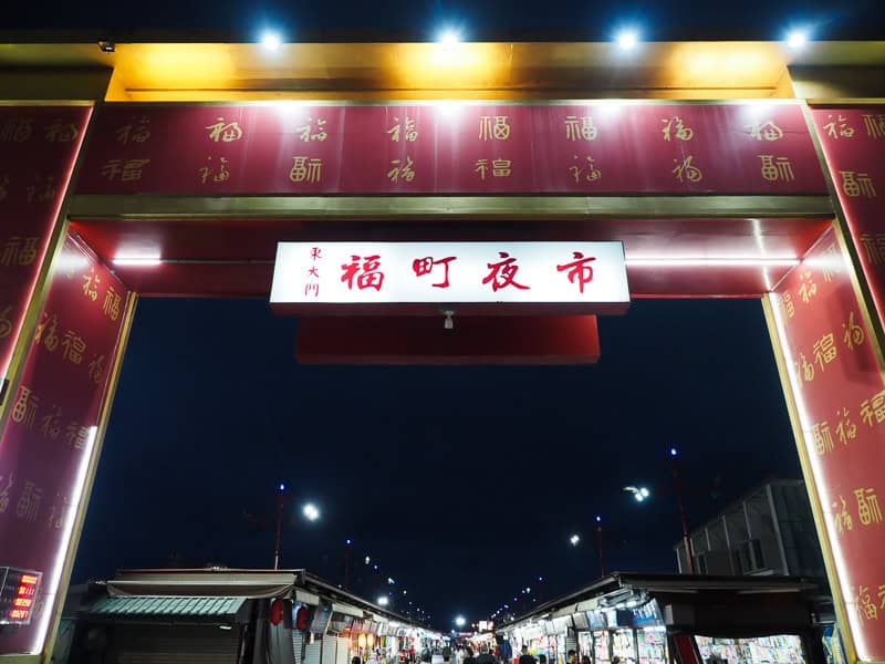 The large entrance gate to Dongdamen Night Market at night with stalls and people visible at bottom, shot at night