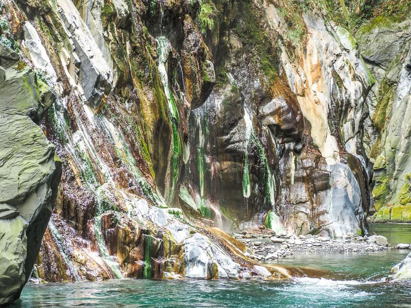 Looking up a river at a colorful hot spring on the opposite side