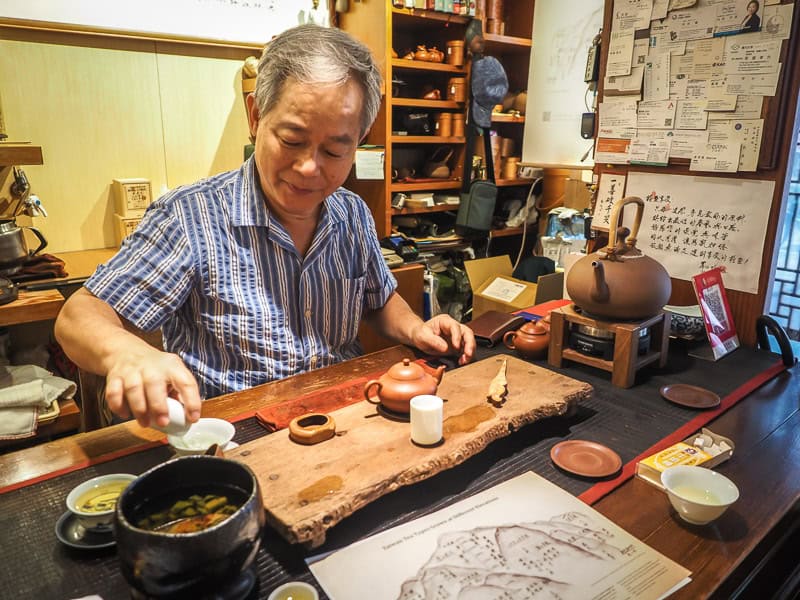A Taiwanese map preparing tea, with a mountain map on the table in the foreground