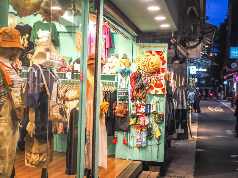 A cute clothing storefront shot from the side, with view looking down a dark lane to its right