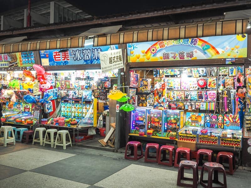 Some games for kids in a night market, with prizes on displays and chairs for sitting to play the games