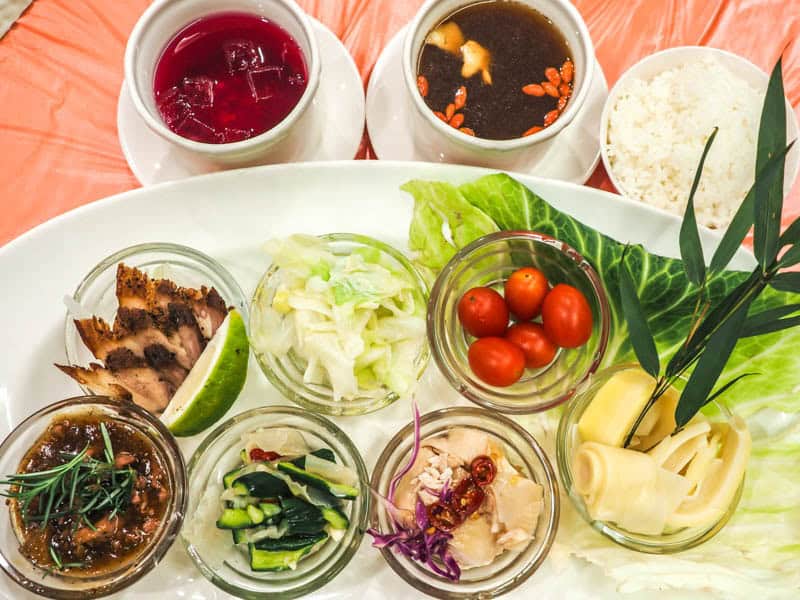 A long white plate with multiple dishes in small bowls on it and more on the side