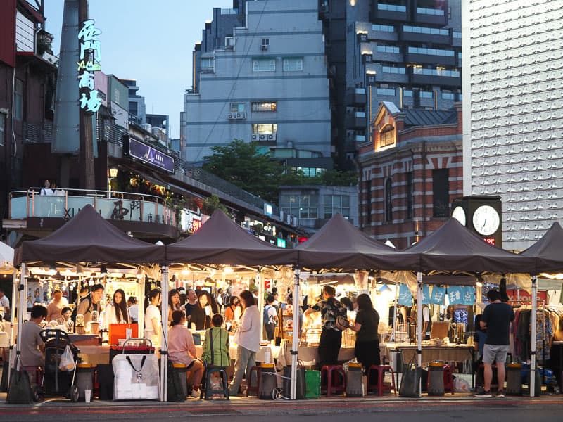 Some people shopping at tents in a craft market in the early evening