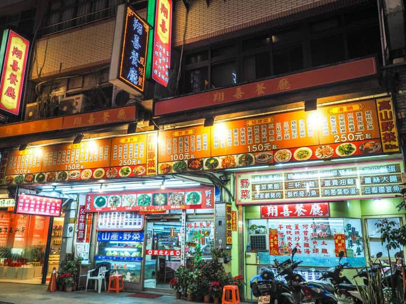 Front of a restaurant in Shuishe at night, with many menu items on the board above the entrance