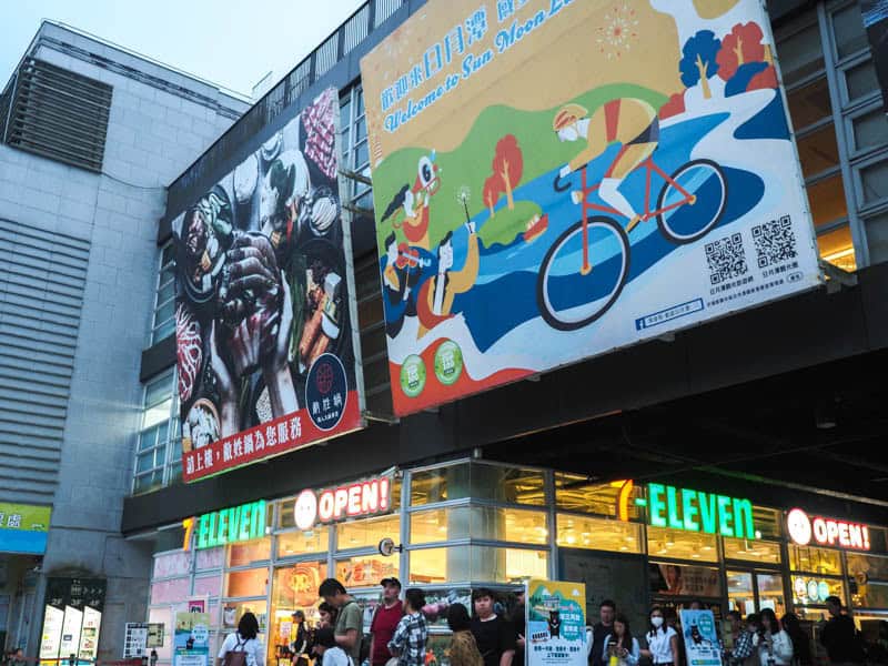 Shuishe bus station at Sun Moon Lake with a 7-Eleven below and passengers waiting