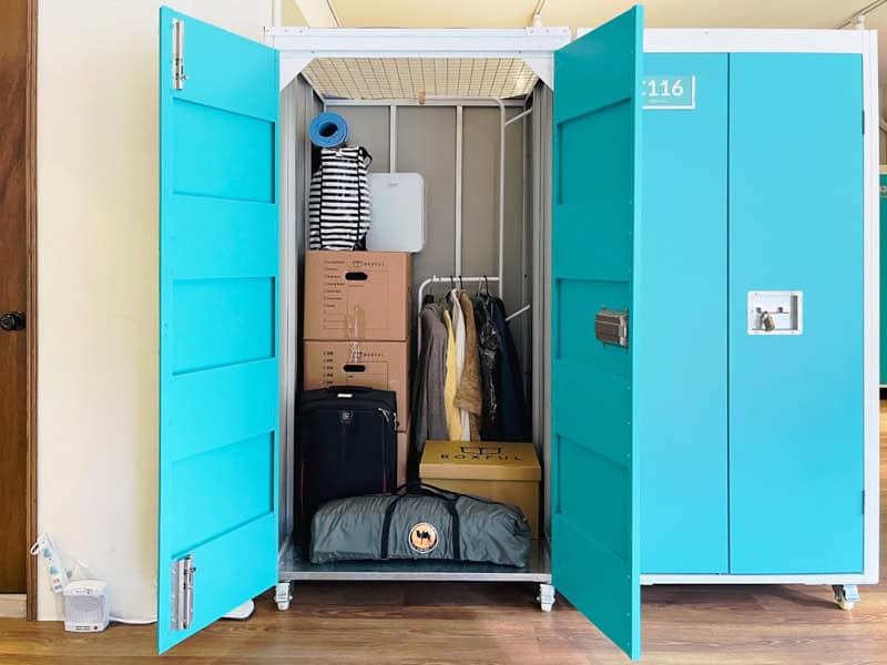 A large baby blue colored storage locker with doors open to reveal contents inside