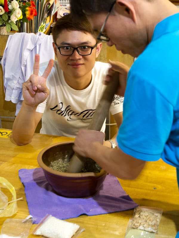 Two men making Hakka pounded tea with a mortar and peste