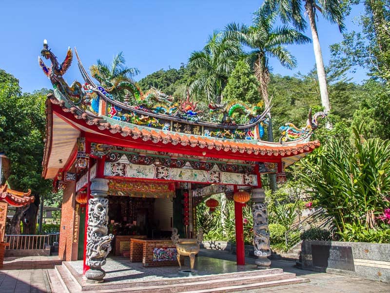 A small Taiwanese temple with palm trees behind it