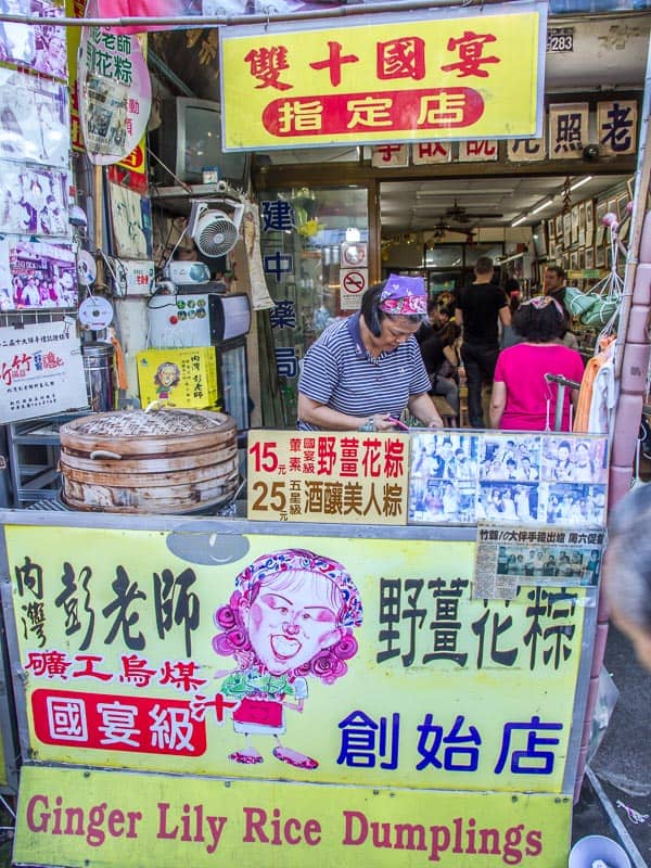 A food stall on Neiwan Old Street with signs advertising its specialty, ginger lily rice dumplings