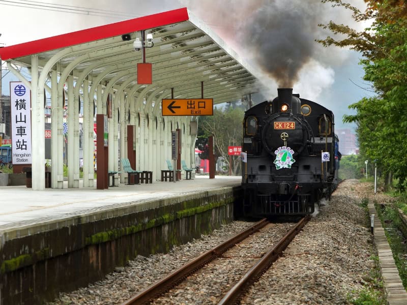 A black locomotive parked at a white and red train station