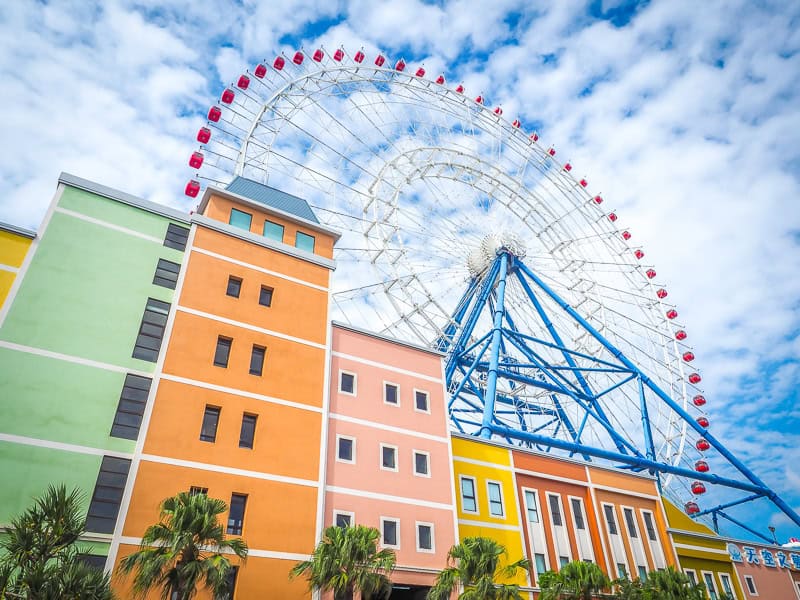 A row of pastel colored buildings with huge Ferris wheel on top