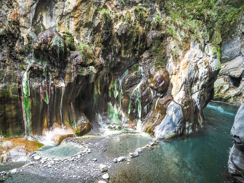 A beautiful collection of hot spring pools at the bottom of a cliff beside a river