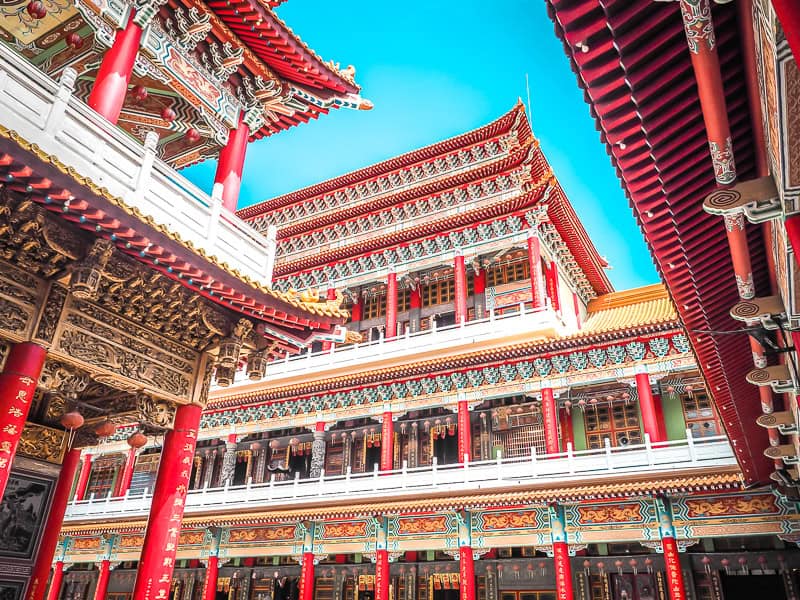 Looking up at the main hall of a large red Taiwanese Matsu temple, with more similar buildings on either side