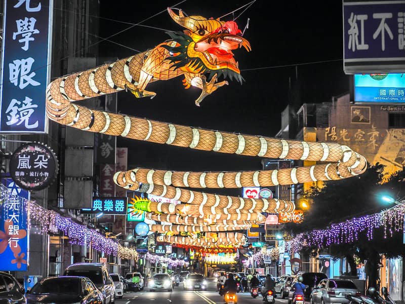 A street in Lukang at night, with a very long dragon lantern hanging above the road and zig-zagging into the distance
