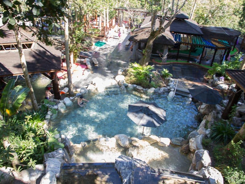 Looking down on an outdoor hot spring facility with trees around it