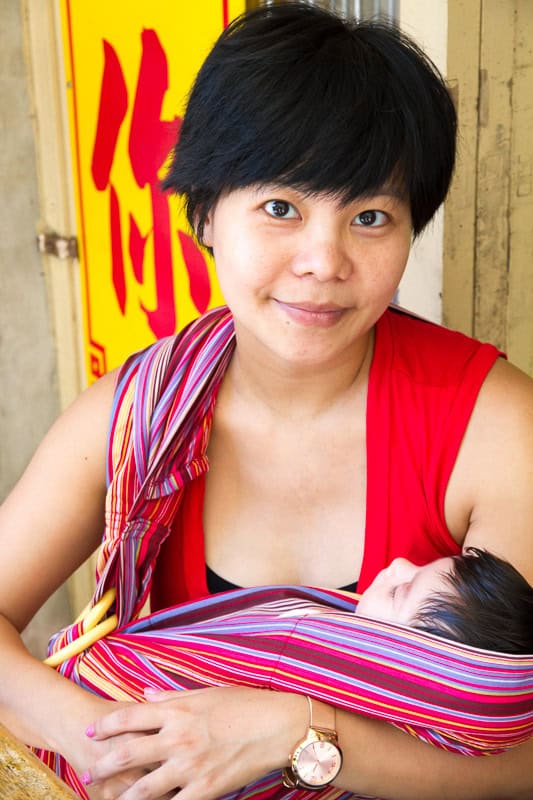 Nick Kembel's wife Emily holding a baby in a carrier and looking at the camera