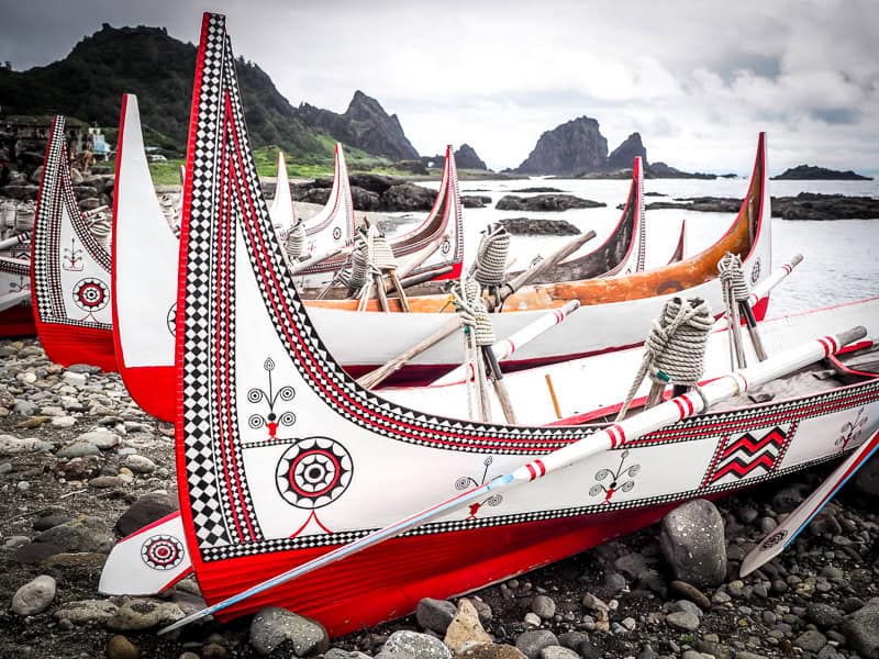 A group of red and white hand-carved canoes on a rocky beach on Orchid Island