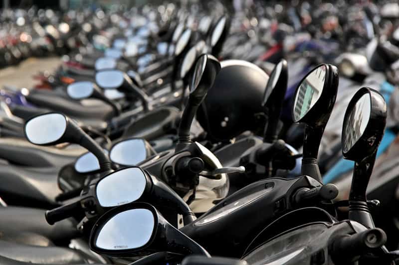 A sea of parked scooters, with many of their rearview mirrors in a row